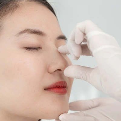 Cirujano midiendo proporciones faciales — análisis de armonía para planificación de rinoplastia